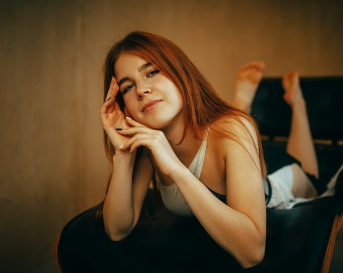 Young woman with red hair lying on a chair