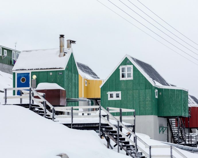green wooden houses on snow covered slope under white skies
