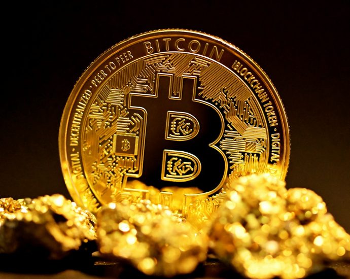 a bitcoin sitting on top of a pile of gold nuggets
