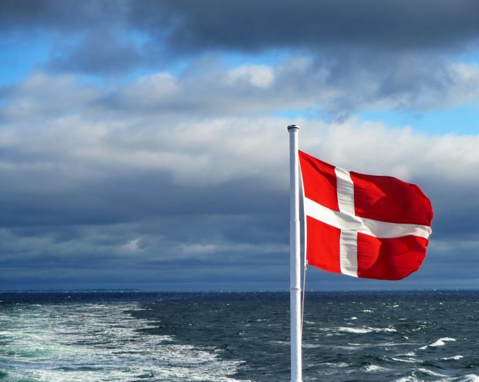 us a flag on flag pole near sea under cloudy sky during daytime