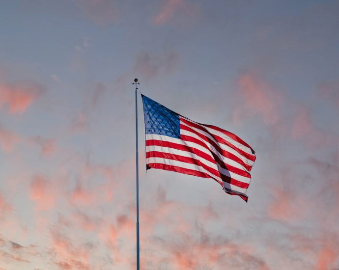 us a flag on pole under cloudy sky
