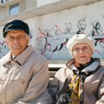 a man and woman standing in front of a wall with graffiti
