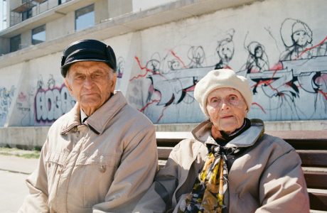 a man and woman standing in front of a wall with graffiti