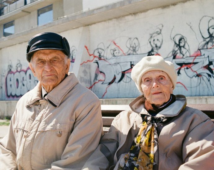 a man and woman standing in front of a wall with graffiti