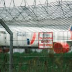 a plane behind a fence with a sign on it