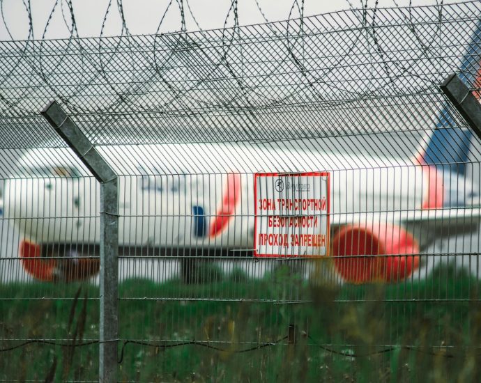 a plane behind a fence with a sign on it