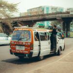 A taxi bus drives on a busy road.