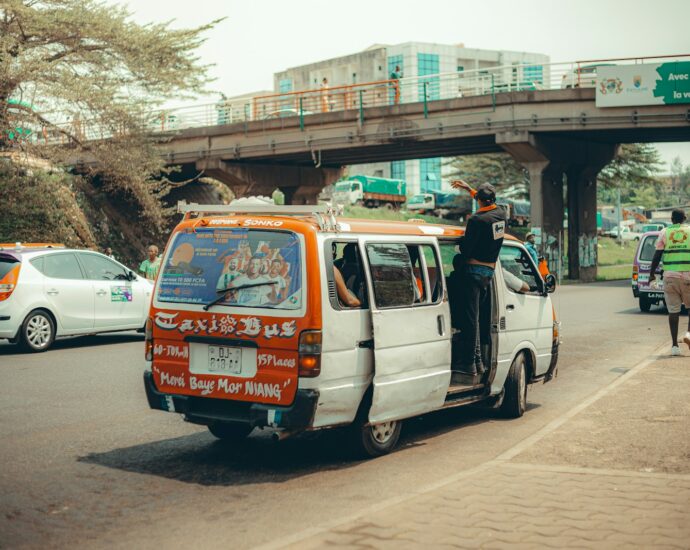 A taxi bus drives on a busy road.