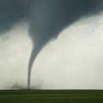 a large tornado is seen in the sky over a green field