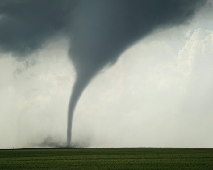 a large tornado is seen in the sky over a green field