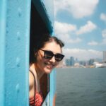 Young woman smiles from a blue window on a boat.