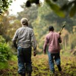 a couple of men walking down a dirt road