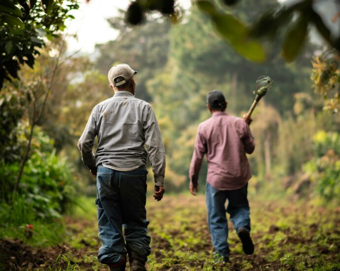 a couple of men walking down a dirt road