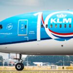 a large blue and white jetliner sitting on top of an airport runway