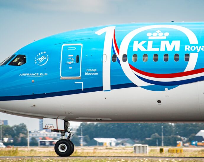 a large blue and white jetliner sitting on top of an airport runway