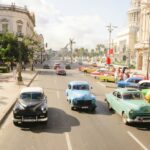 three assorted-colored vintage car on road