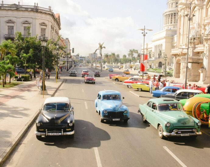 three assorted-colored vintage car on road