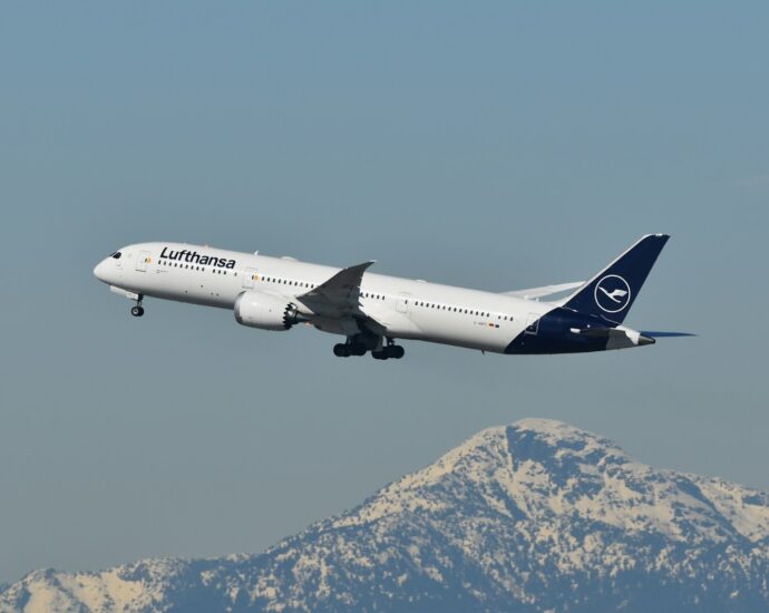 A large jetliner flying over a mountain range