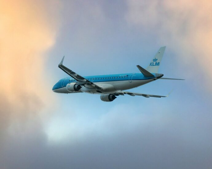 a blue and white airplane flying through a cloudy sky