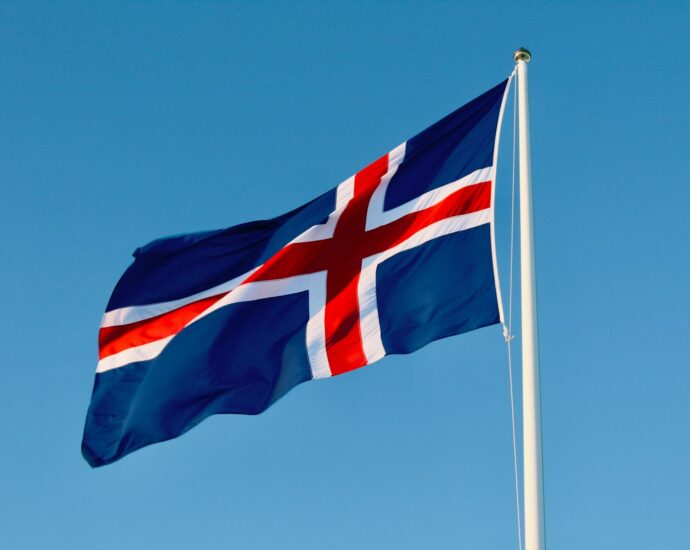 a flag flying in the wind with a blue sky in the background