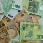 Scattered euro banknotes of 100 and 50 denominations.