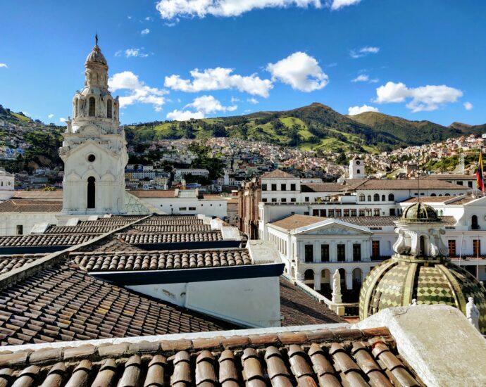 white and brown concrete building near green mountain under blue sky during daytime