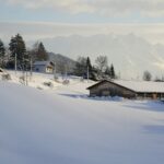 a snow covered hill with a house in the distance
