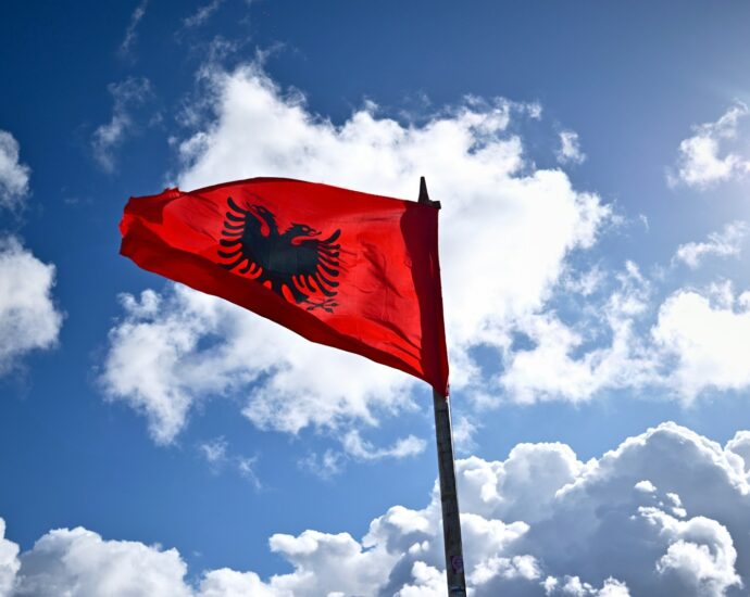 Albanian flag waving against a cloudy blue sky