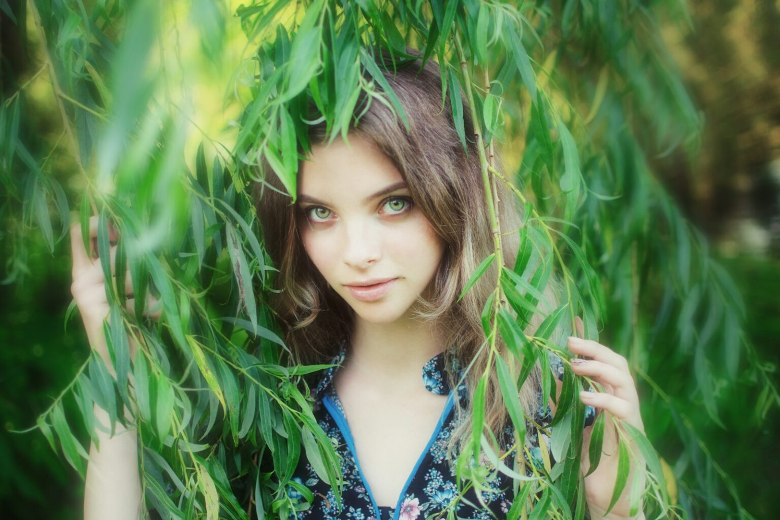 Young woman peeking through green leaves