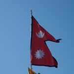 Two flags flying in the wind on a clear day