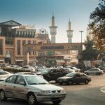 Bustling Tehran street scene with cars, mosque minarets, and traditional architecture.