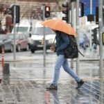 A man walks with an orange umbrella on a rainy day in Istanbul, Türkiye.