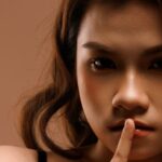 Close-up portrait of a woman signaling silence, creating a mysterious aura.