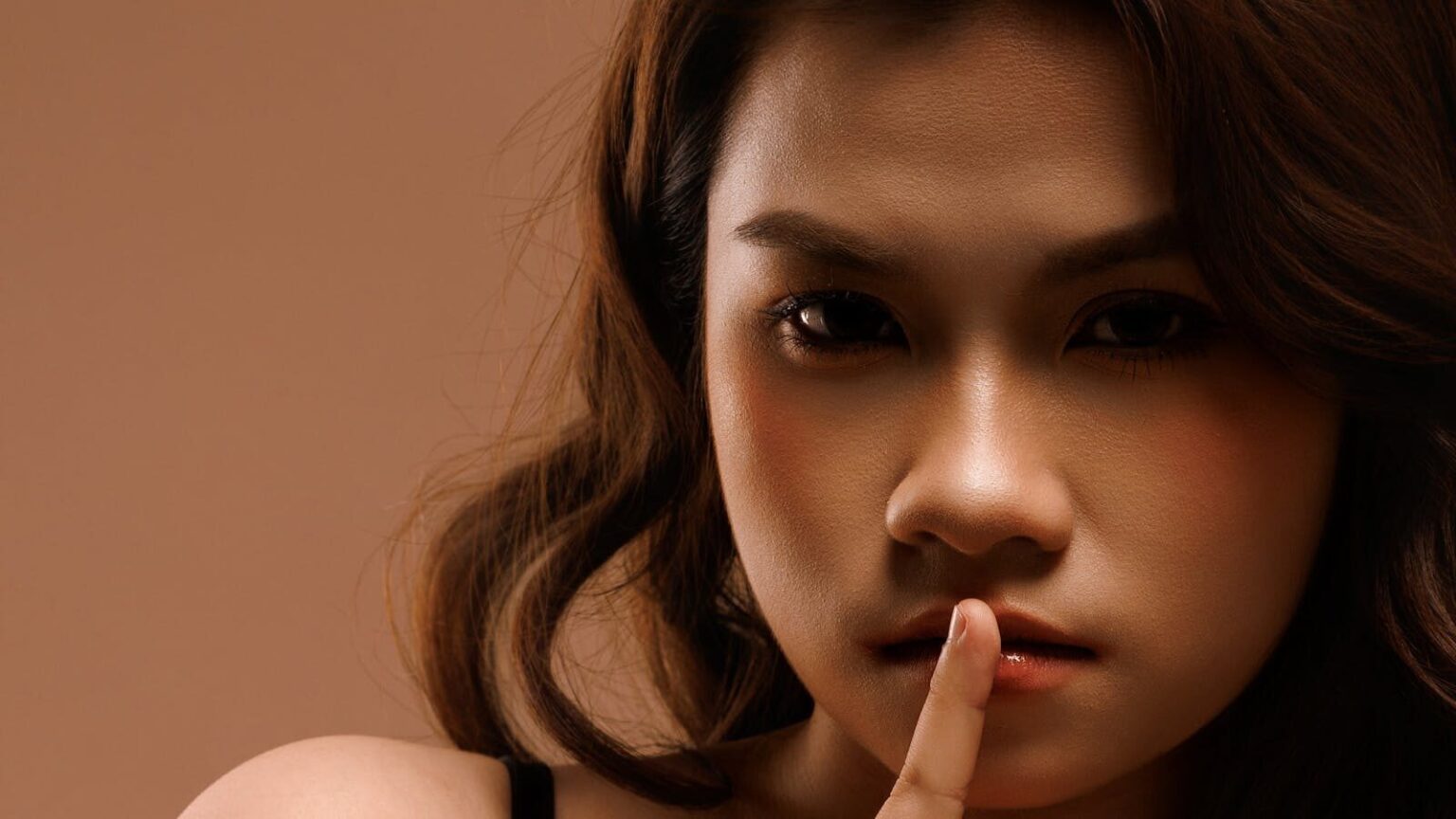 Close-up portrait of a woman signaling silence, creating a mysterious aura.