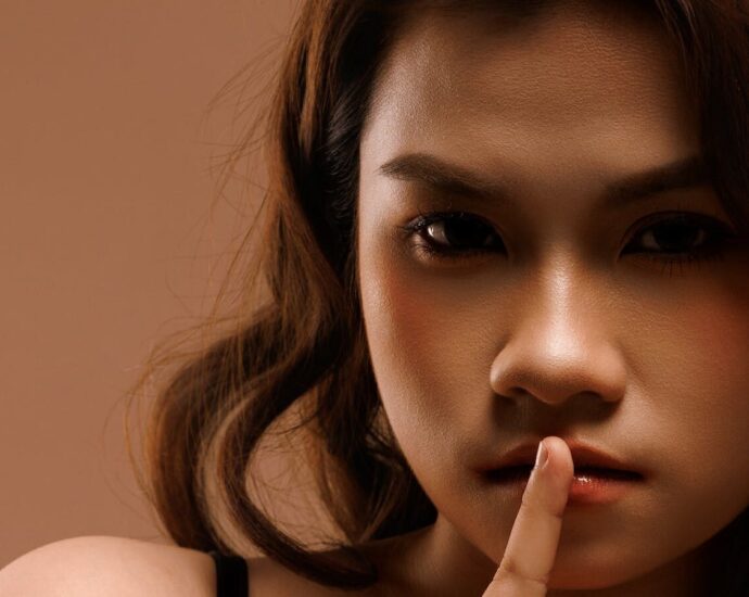Close-up portrait of a woman signaling silence, creating a mysterious aura.