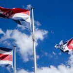 Three national flags waving against a blue sky