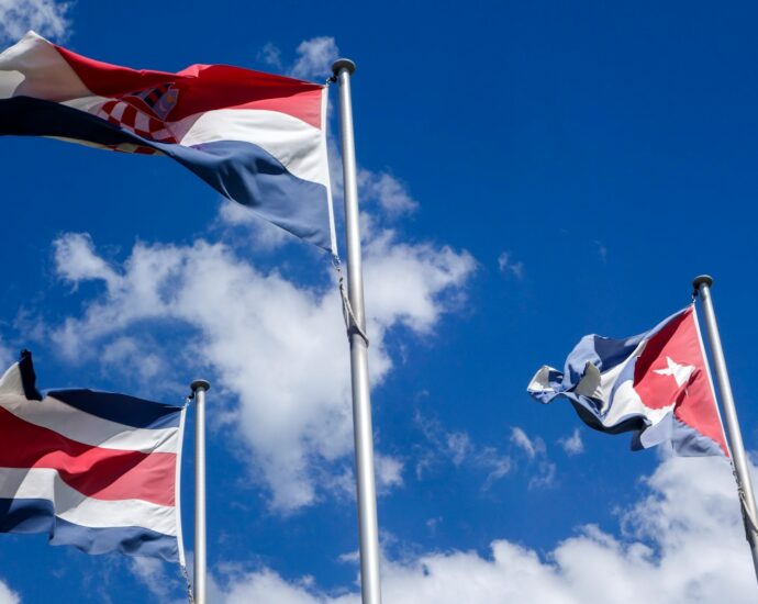 Three national flags waving against a blue sky