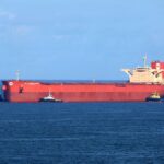 a large red cargo ship in the middle of the ocean
