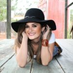 A woman in a hat lying on a wooden deck.
