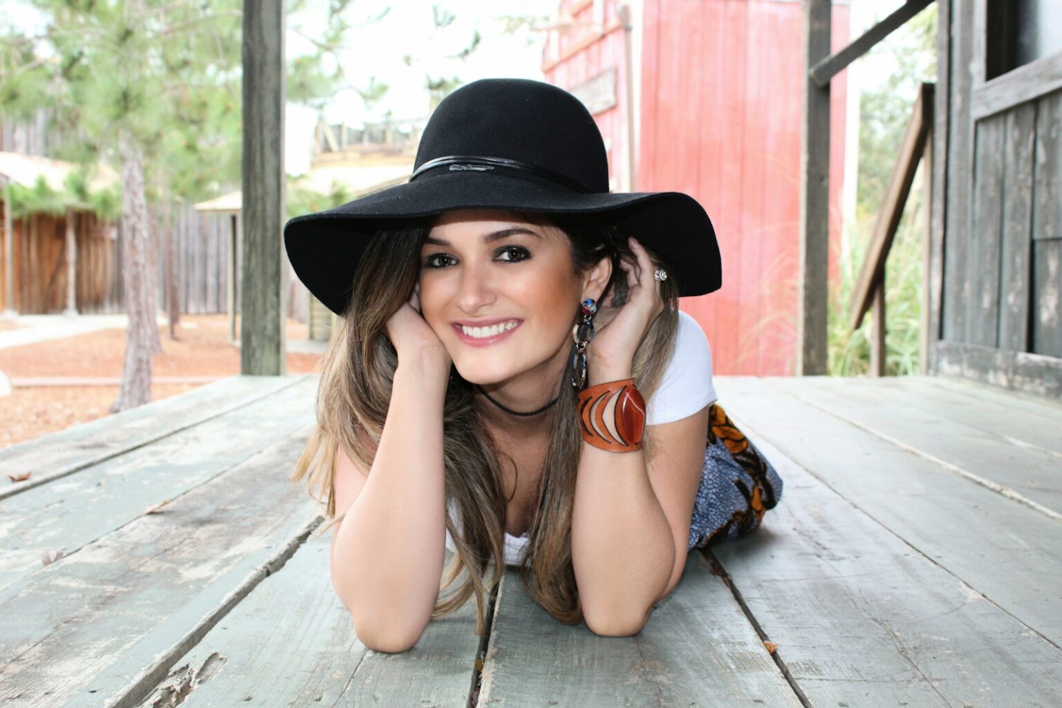A woman in a hat lying on a wooden deck.