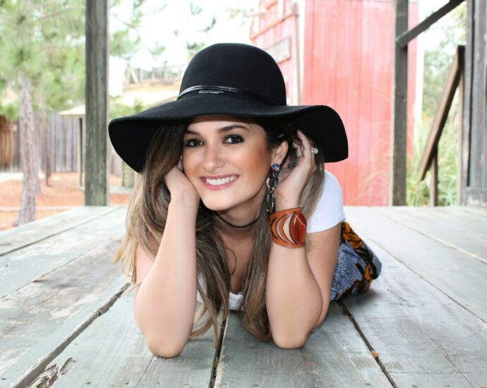 A woman in a hat lying on a wooden deck.
