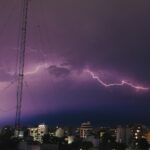 a lightning storm is seen over a city at night