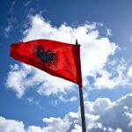 Albanian flag waving against a cloudy blue sky