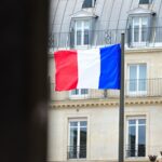 A flag flying in front of a tall building