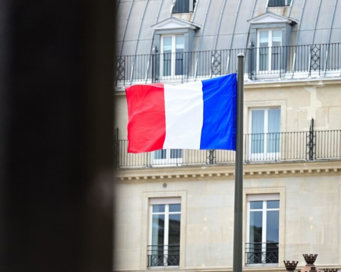 A flag flying in front of a tall building