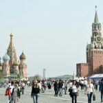Tourists gather at Moscow's iconic Red Square, featuring St. Basil's Cathedral and Spasskaya Tower.