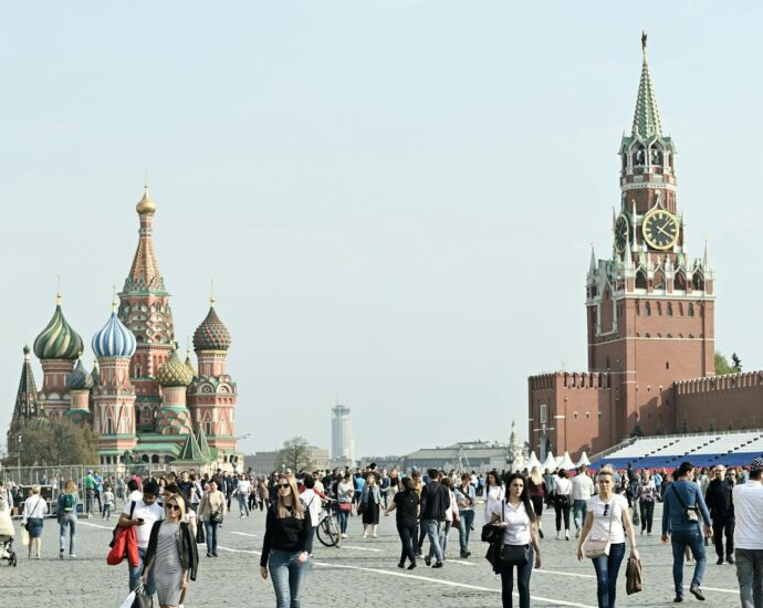 Tourists gather at Moscow's iconic Red Square, featuring St. Basil's Cathedral and Spasskaya Tower.