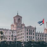 View of the historic Hotel Nacional in Havana, Cuba with a waving Cuban flag and clear sky.