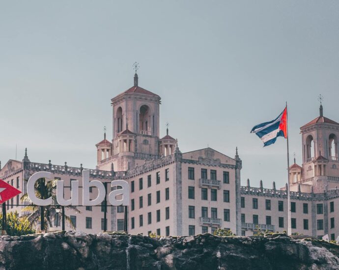 View of the historic Hotel Nacional in Havana, Cuba with a waving Cuban flag and clear sky.