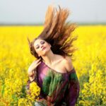 Vibrant portrait of a woman in a yellow flower field, exuding happiness and freedom.